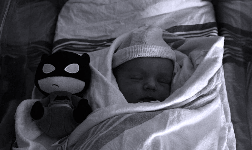 baby and stuffed batman in black and white